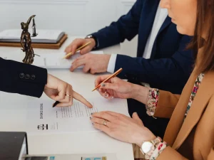 A woman signing a divorce decree with the help of her female lawyer.