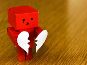 A toy robot holding a broken heart.