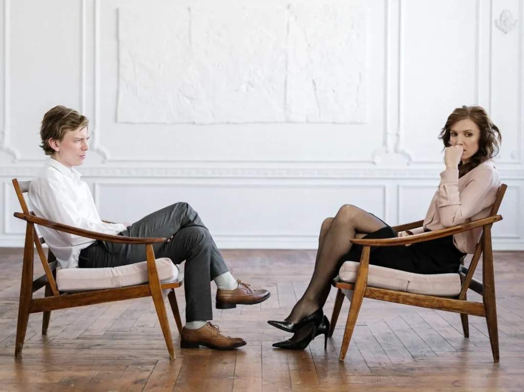 A man and a woman sitting in chairs looking upset.