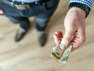 A man holding a folded up 10 dollar bill.
