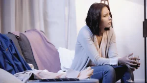 A woman sitting on a couch looking upset and sad.