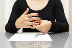 A woman in a black shirt takes off her wedding ring.