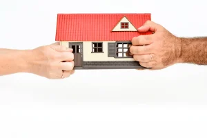 A pair of a man and woman hands fighting over a house.