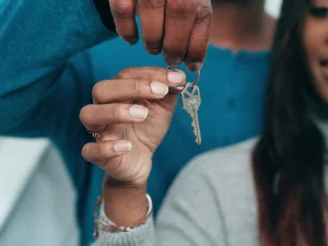A couple holds the key to a house.