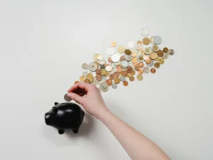A hand putting change into a piggy bank.