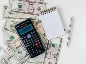 A pen, cash, calculator, and notepad lay on a table in an asset evaluation.