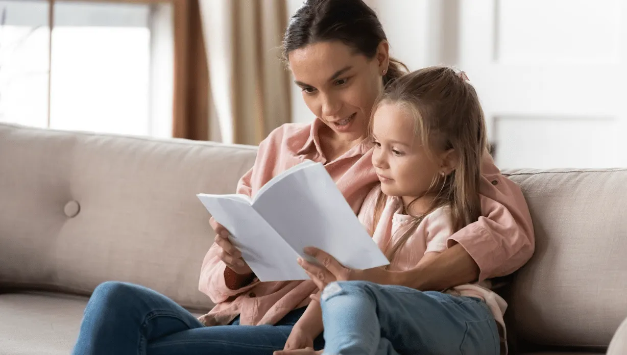 A mother and daughter spending time together reading a book. If you’re a mother fighting a custody battle, our divorce lawyers for women can help you build a strong child custody case.