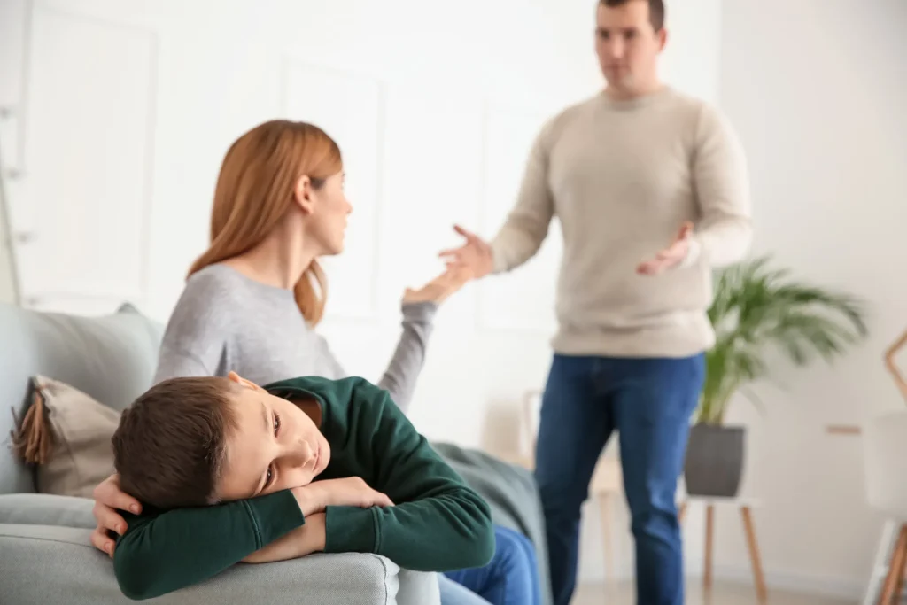Sad little boy with parents arguing at home. If you’re a mother facing a custody battle, the divorce attorneys for women’s needs are here to help and support you.