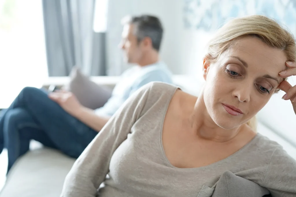 A woman sits away from her partner, unhappy and considering talking to a divorce attorney.