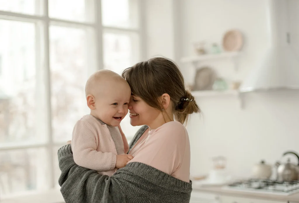 Young mom smiling and hugging baby at home. We know that there is nothing more precious than your child, that’s why the women divorce attorneys at WSM will fight to the end for a favorable child custody result.