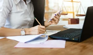 Female lawyer using mobile phone and laptop to find legal information