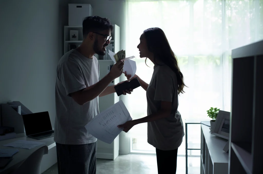 a couple arguing with one another and holding money and paperwork.