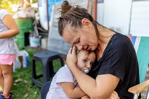 A mother crying and holding her child close to her.