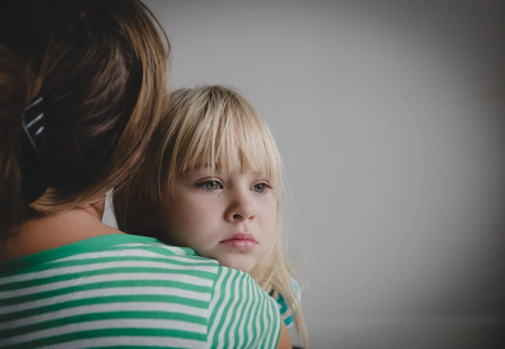 mother comforting and protecting her crying daughter.