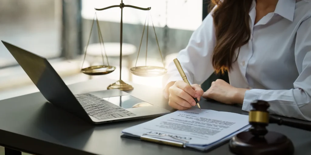 An attorney writing at her desk with the scales of justice.