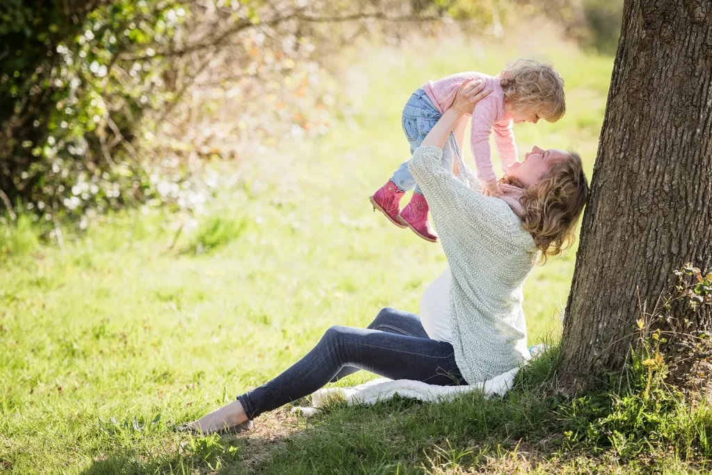 A mom holding up her child while sitting outside.
