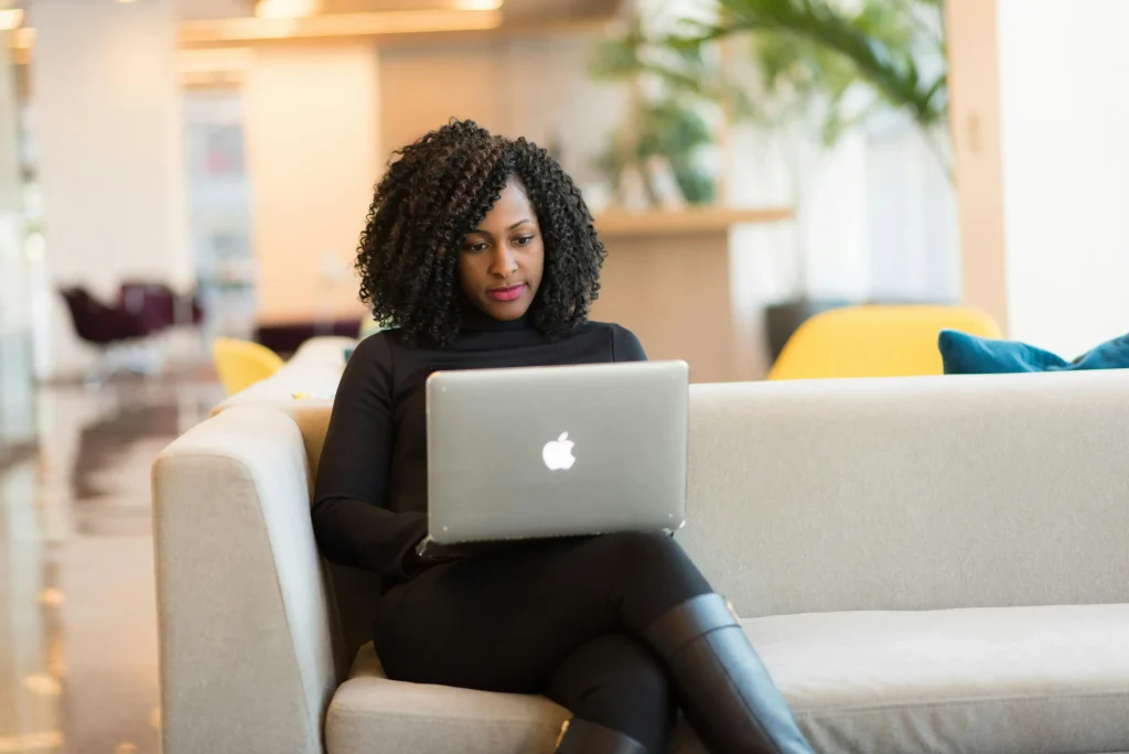 An attorney sitting on a couch and working on her laptop.