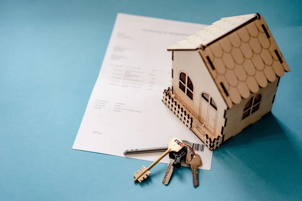Paperwork with a miniature house and keys sitting on it.