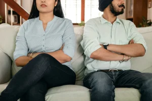 A couple sitting on a couch with their arms crossed.