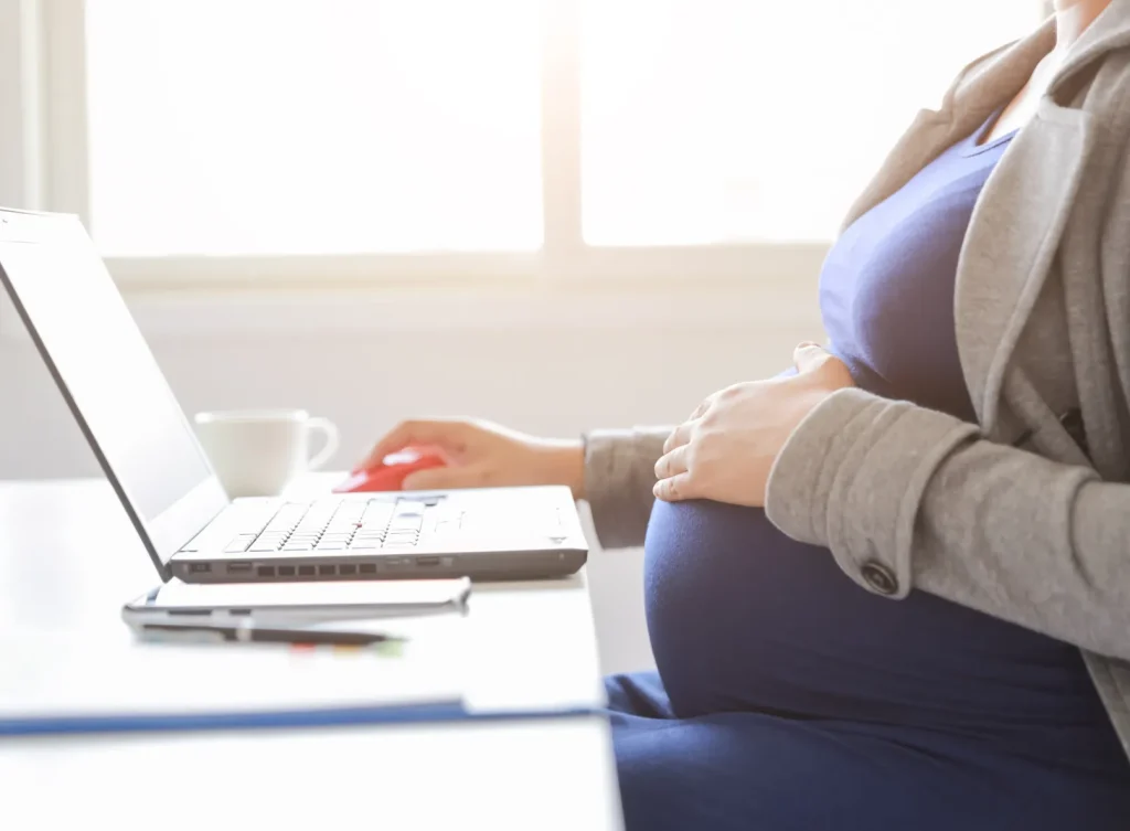 A pregnant woman working on the computer.