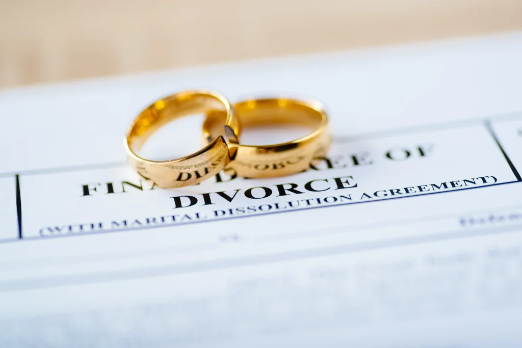 Divorce decree document with two gold rings resting on top.