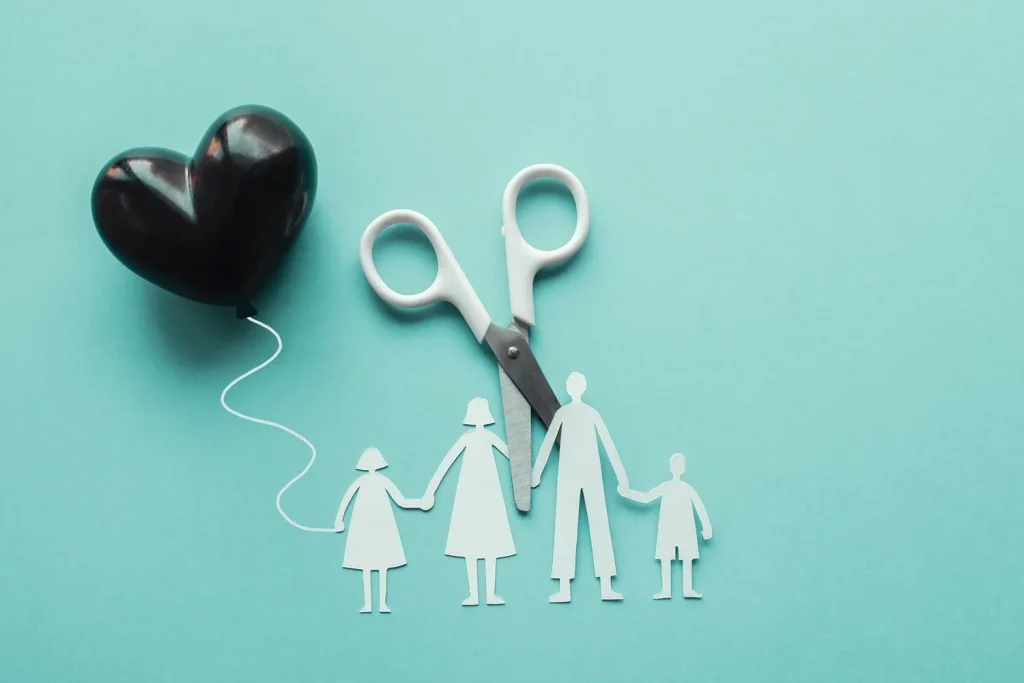 A paper family with scissors and a black heart balloon.
