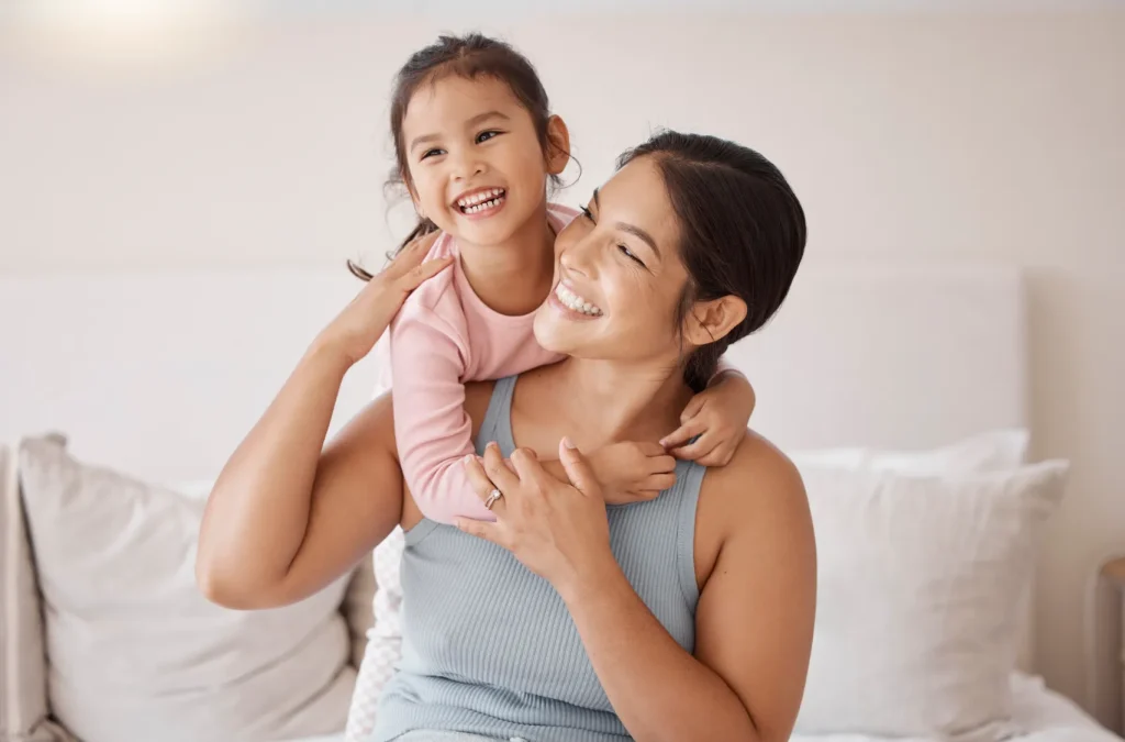A mom and her daughter smiling together.