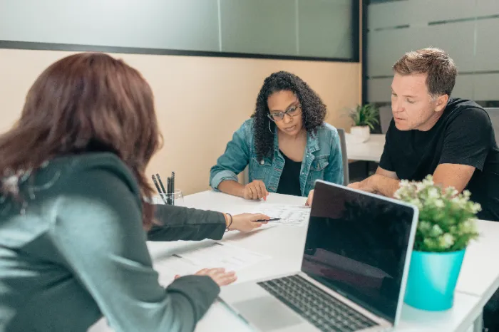 An attorney working with her clients with signing paperwork.