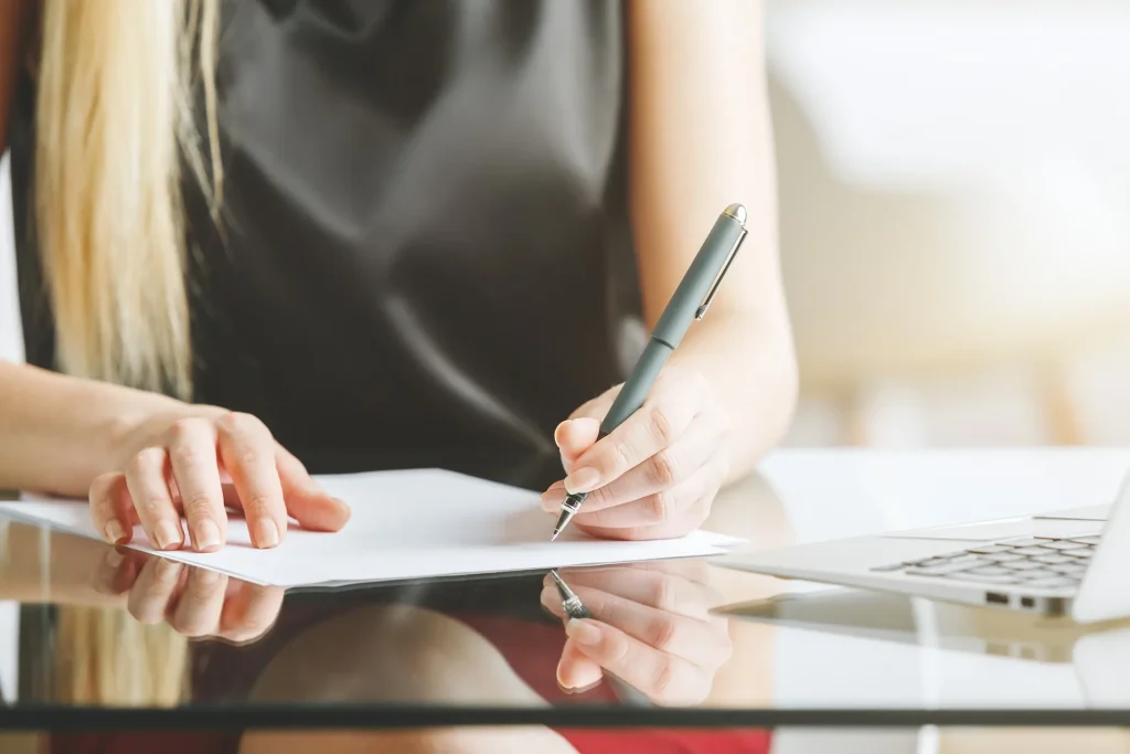 A woman holding a pen signing papers.