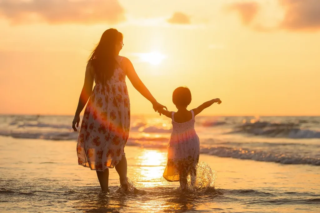 A mom walking on the beach with her child.