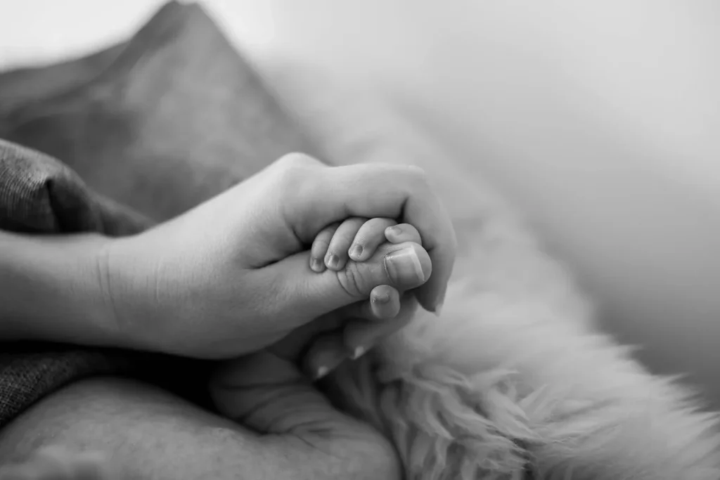 A mother holding her baby's hand.