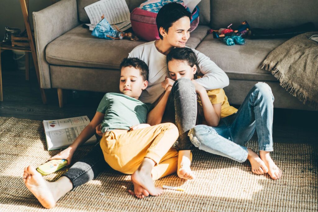 A mom with her two kids on the living room floor.