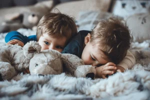 Two young boys cuddling stuffed animals.