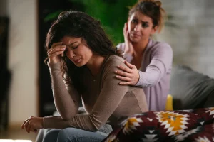 A distraught woman and another woman comforting her.