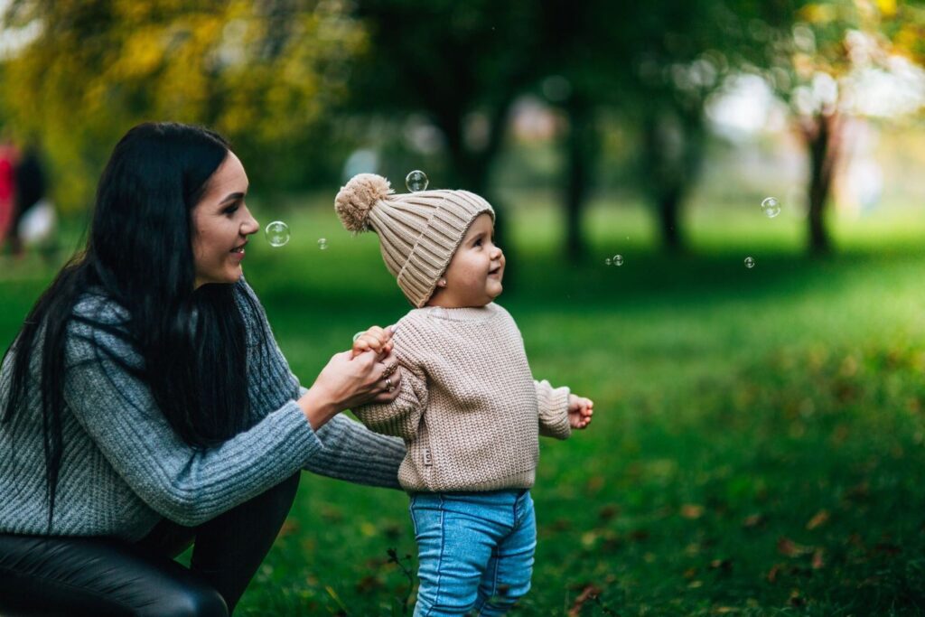 A mom and her child outside blowing bubbles.