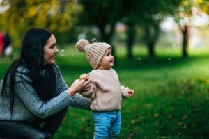 A mom and her child outside blowing bubbles.