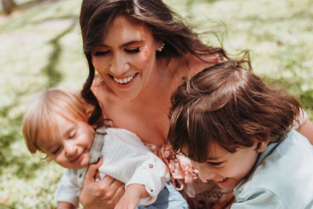 A mother laughing and playing around with her two children..