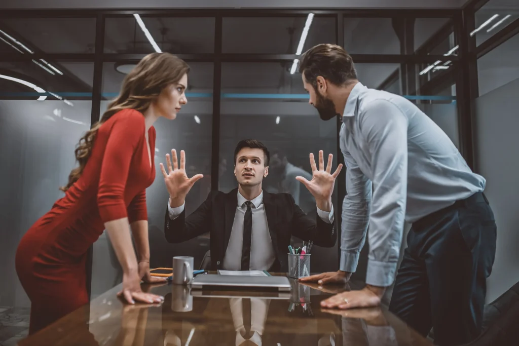 A couple arguing in front of a lawyer in a meeting.