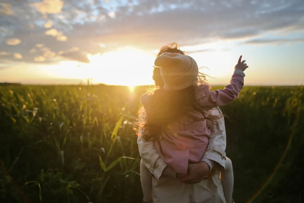 A little girl and her mom in grass fields.