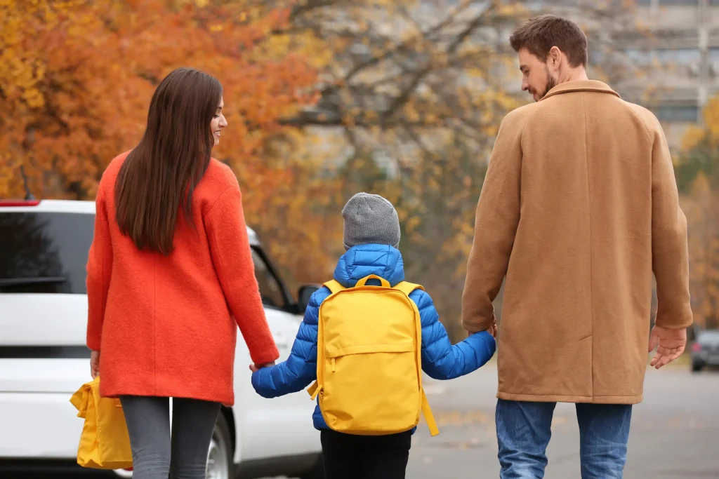 A child with both his parents walking to school.