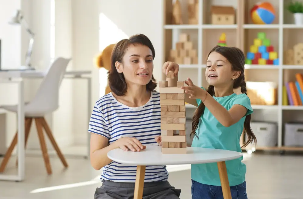 A woman and child play Jenga joyfully.