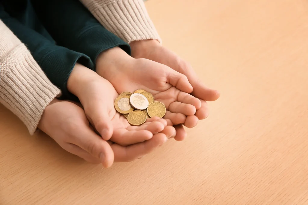 Mother and child hands holding coins, symbolizing child support after divorce.
