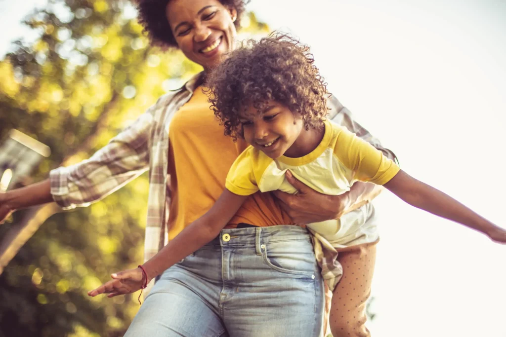 A mom holding her child and playing outside.