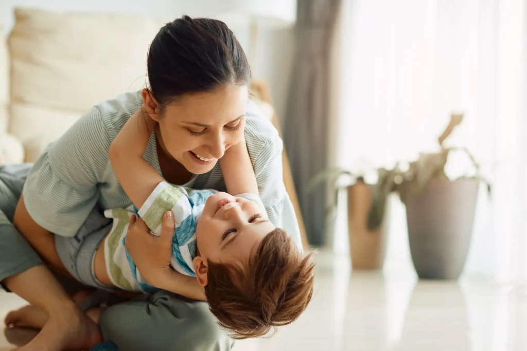 A smiling mother playing with her young son.