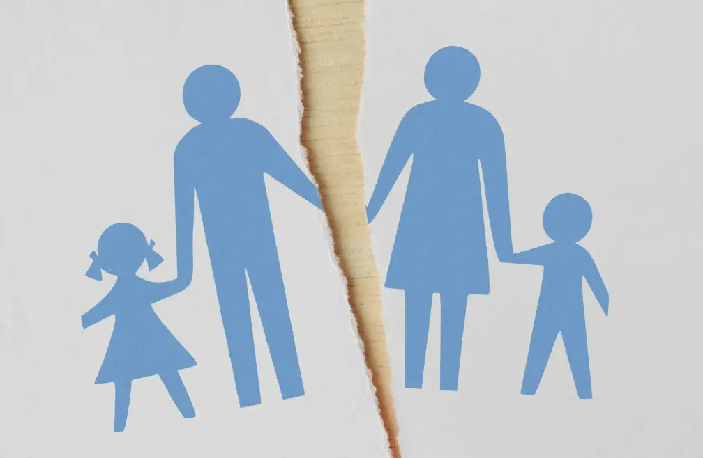 Blue family silhouettes torn down the middle on white paper, symbolizing separation.