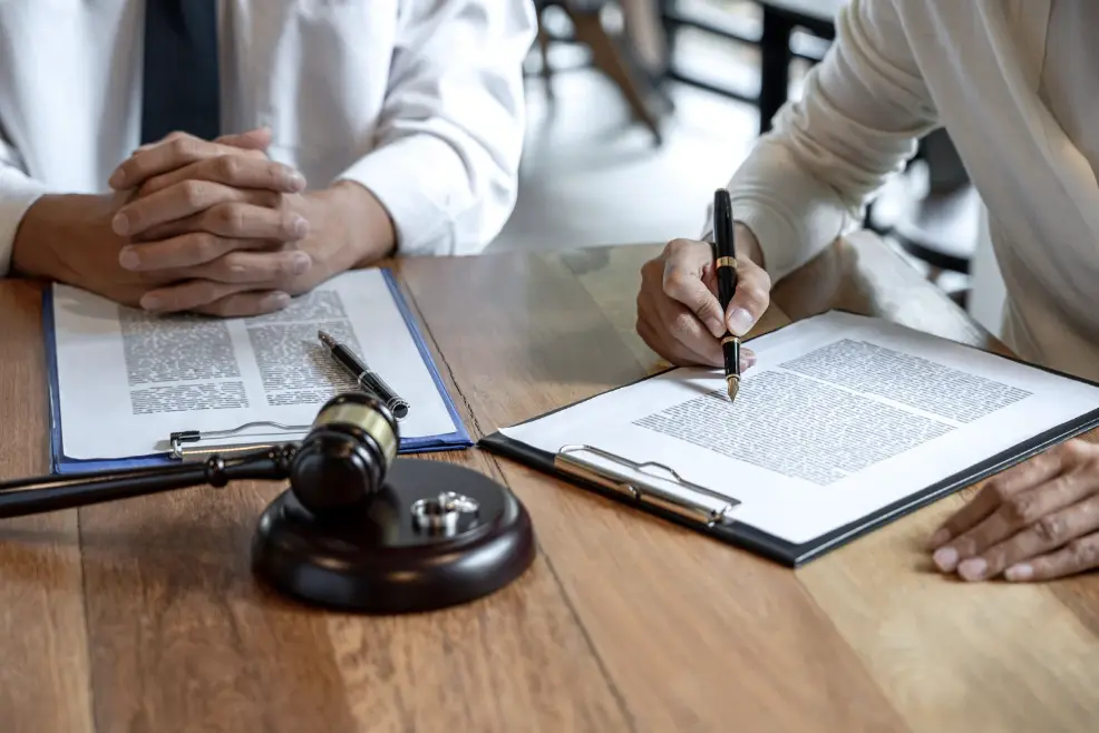 Two people at a table with legal documents,during divorce process.