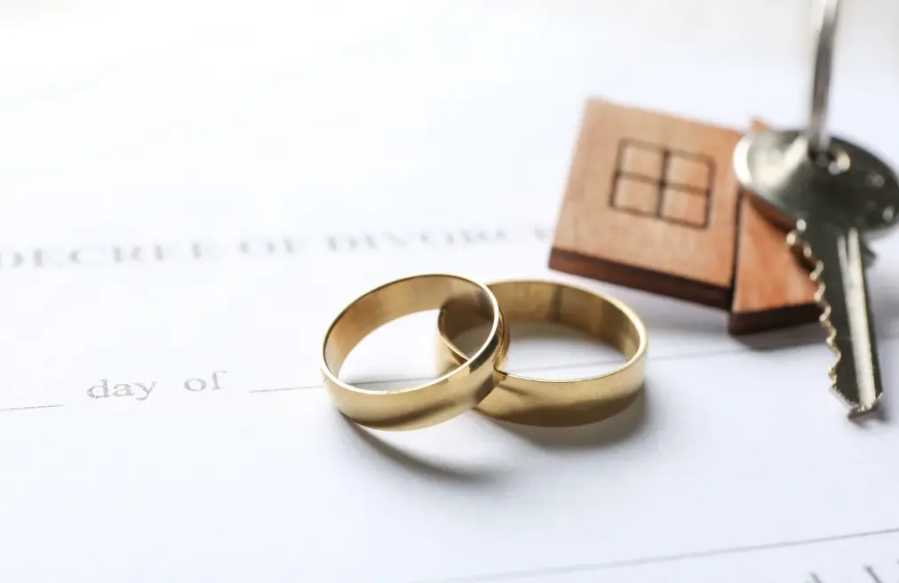 Two gold wedding rings on a divorce decree with keys, illustrating separate and marital property.