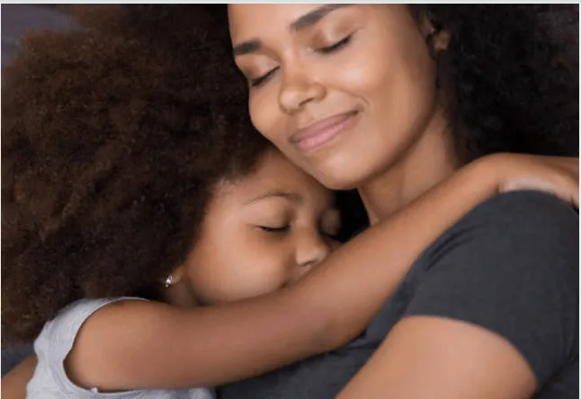 A smiling mom giving her young daughter a hug.